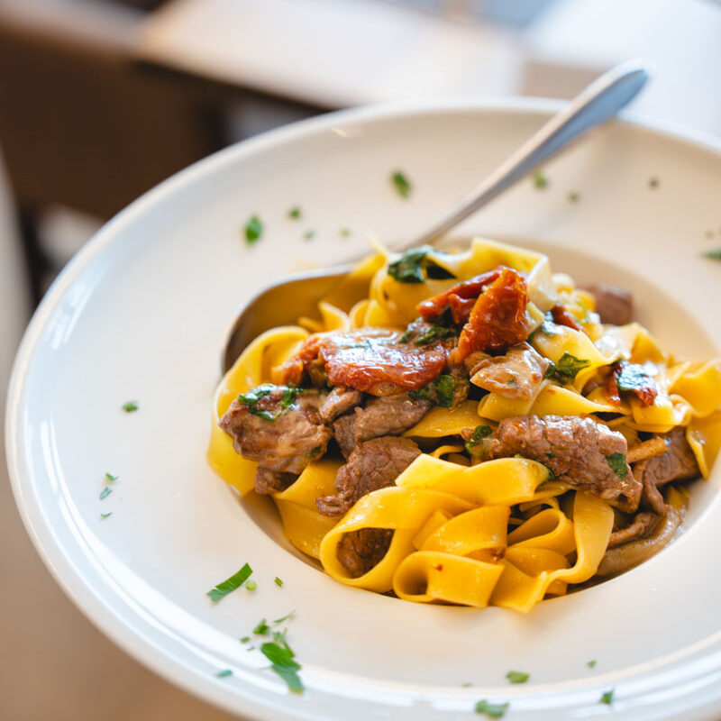 Ein Teller mit Pasta und Fleisch angerichtet